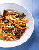Piece of beef with carrots and spring onions on dish