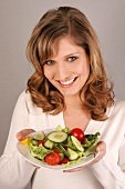 Frau mit langen Haaren hält einen Teller Salat