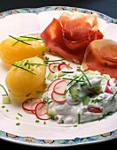 Boiled potatoes with cottage cheese dip and ham on plate