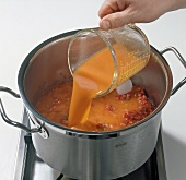 Adding pepper stock to meat in pot for preparation of consomme, step 7