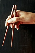 Close-up of woman's hands holding chopsticks between thumb, index and middle finger punch