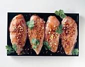 Four pieces of meat marinated with parsley on top, overhead view