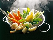 Carrots, cauliflower and among others vegetables being steamed in silver pot
