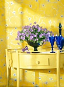 Violet flower vase on table against yellow floral printed wall