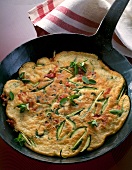 Zucchini pancake with herb in frying pan