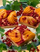Square shape cakes garnished with sliced peach and red currants on plate