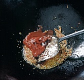 Tomato and soy sauce with chopped garlic, ginger root and chillies fried in wok, step 3