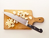 Minced garlic with garlic cloves and knife on wooden board