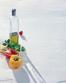 Bottle of oil, halved bell peppers, rice, herbs and tomato on white background