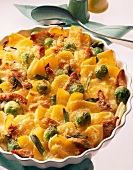 Vegetables and potato casserole with Brussels sprouts, turkey breast and gouda on bowl