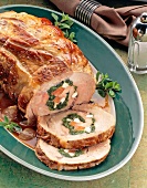 Slices of pork with spinach, sauce and herbs on serving dish