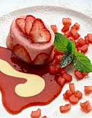 Close-up of rhubarb and strawberry mousse with strawberry slices and mint on plate