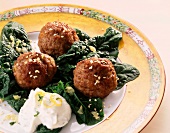 Meatballs with spinach and sesame seeds on plate