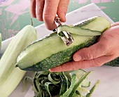 Cucumber being peeled with vegetable peeler