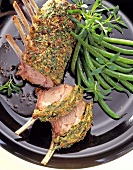 Close-up of rack of lamb with herb crust and beans on plate