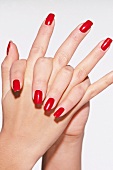 Close-up of woman with hands clasped wearing red nail paint