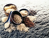 Diverse Reissorten in Schüsseln und ohne auf Stein, nah