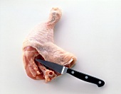Cutting bone in chicken thigh on white background