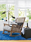 Schaukelstuhl aus Holz am Fenster, grau gestreift, Teppich blau