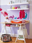 Wooden folding table with shelf and clothes in front of violet wall