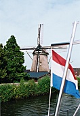 Blick auf Windmühle am Ufer, Fluss, niederländische Flagge, Holland