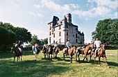 Menschengruppe reitet auf Wiese vor Schloss, Sommer, Frankreich