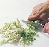Mustard cabbage being cut into narrow strips with knife, step 2