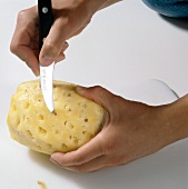 Pineapple eyes being removed with knife, step 4