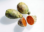 Green conical shaped cactus figs with black spots on white surface, overhead view