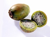 Whole and halved green cactus figs on white background