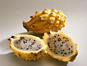 Whole and halved spiny yellow cactus figs with seeds on white background