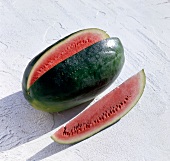 Watermelon with narrow slice cut out on white surface