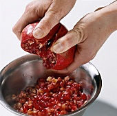 Close-up of hand's deseeding pomegranate in bowl