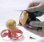 Tamarillo being peeled with knife, step 1