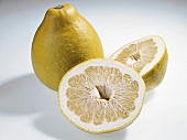 Whole and halved yellow and green pomelo on white background