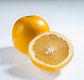 Whole and halved grapefruit with yellow flesh on white background