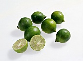 Whole and halved green limequat on white background