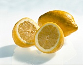 Whole and halved lemons on white background