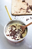 Chopped chocolates being added into hot cream in pan
