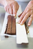 Close-up of chef cutting ganache with the help of ruler