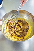 Mixed butter and cocoa being mixed with whisk for preparing chocolate parfait