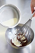 Heated cream being mixed with melted dark chocolate