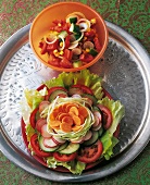Various coloured vegetables salad on plate and bowl