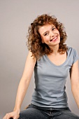Portrait of cheerful woman with short dark curly hair smiling with head cocked