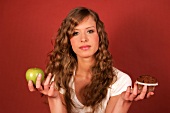 Woman holding apple and muffin in hands