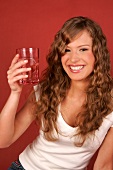 Pretty woman holding glass of water, looking at it and smiling