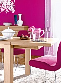 Extended light wood table and chair on white carpet against pink wall