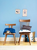 Kissen in Braun und Blau auf Stühlen aus Holz, Wand blau