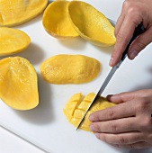 Close-up of hand cutting mango on chopping board
