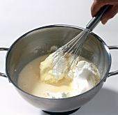 Yogurt being whisked in liquid dough